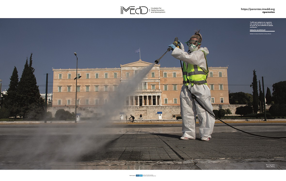 Μια γυναίκα μπροστά από το κτήριο της Βουλής φοράει μια ειδική στολή και με ένα πιεστικό νερου καθαρίζει το πεζοδρόμιο