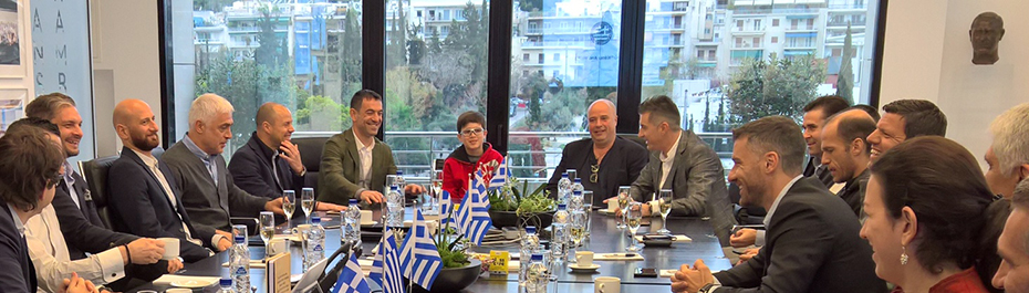 Μέλη της ελληνικής ομάδας των πρωταθλητών του Euro 2004 συνομιλούν και χαμογελούν με μέλη του Ιδρύματος Σταύρος Νιάρχος σε αίθουσα συνεδριάσεων