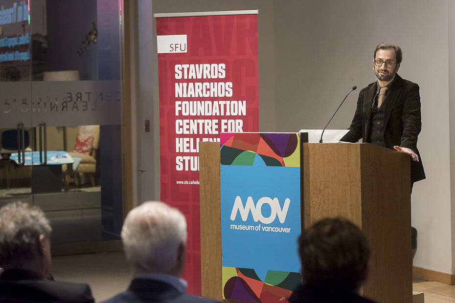 Ένας άνδρας σε μια εξέδρα μιλάει σε ένα καθιστό κοινό στο Μουσείο του Βανκούβερ