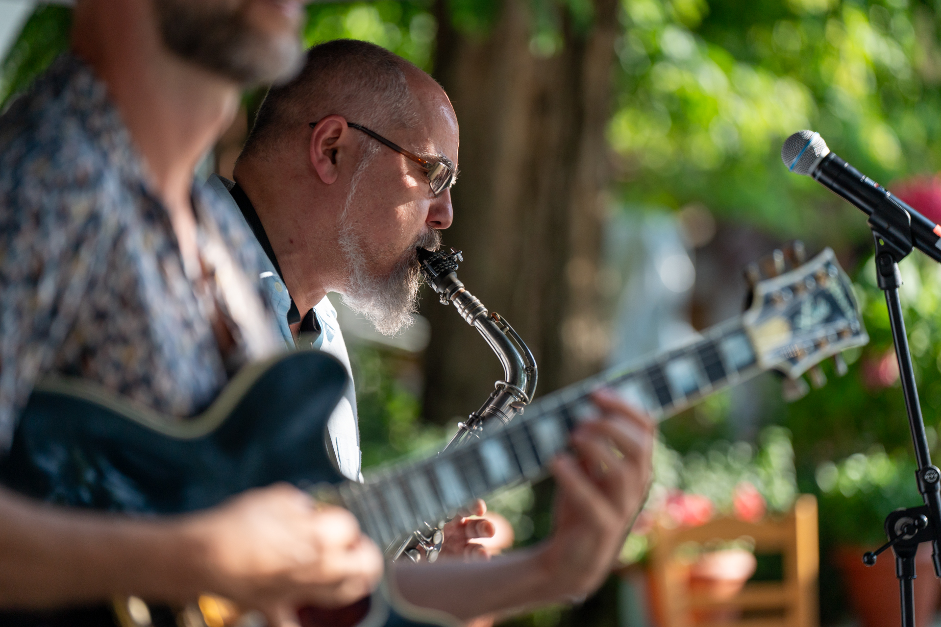 Ένας άντρας παίζει σαξόφωνο δίπλα σε έναν άντρα που παίζει κιθάρα