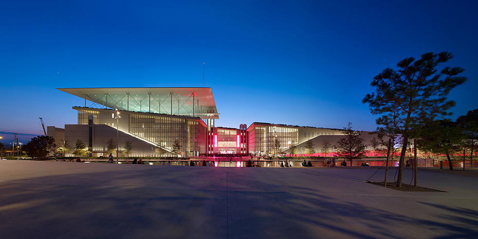 Η πρόσοψη ενός μεγάλου γυάλινου κτηρίου φωτισμένου τη νύχτα 