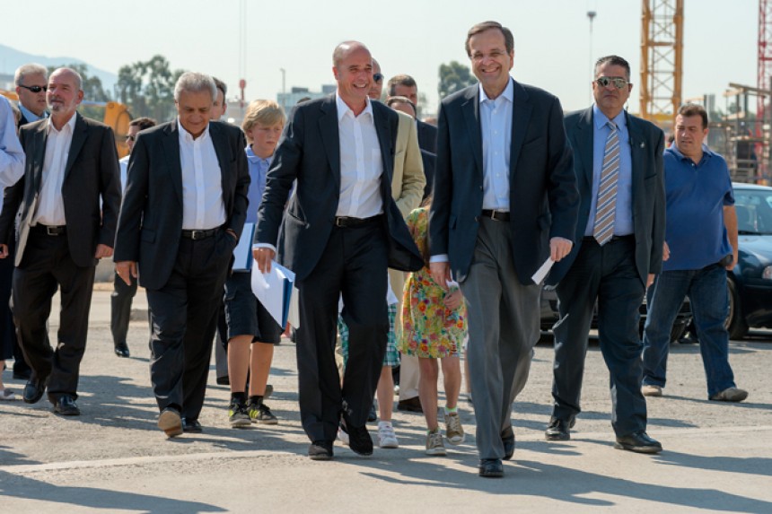 Ο Ανδρέας Δρακόπουλος, πρόεδρος του Ιδρύματος Σταύρος Νιάρχος, και ο Αντώνης Σαμαράς, πρωθυπουργός της Ελληνικής Δημοκρατίας, περπατούν με μια ομάδα ανθρώπων και χαμογελούν