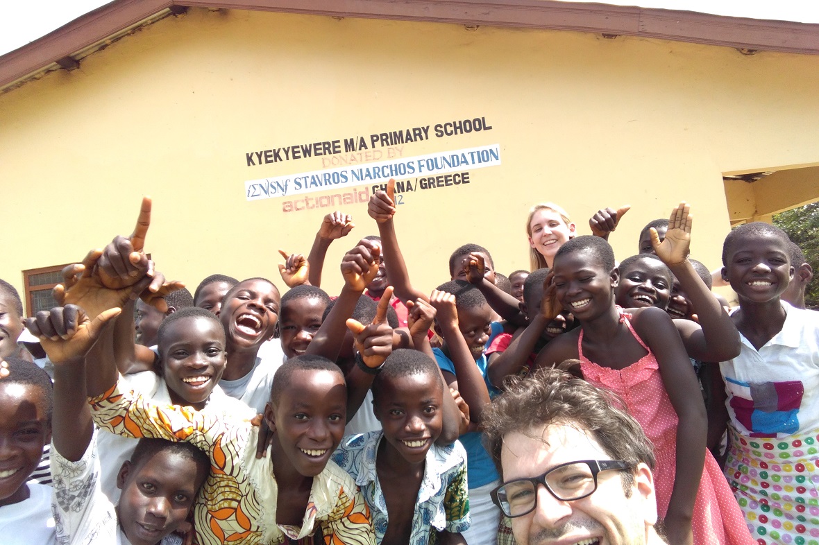 Μέλος του Ιδρύματος Σταύρος Νιάρχος τραβάει φωτογραφία με πολλά χαμογελαστά παιδιά στη Γκάνα μπροστά από ένα δημοτικό