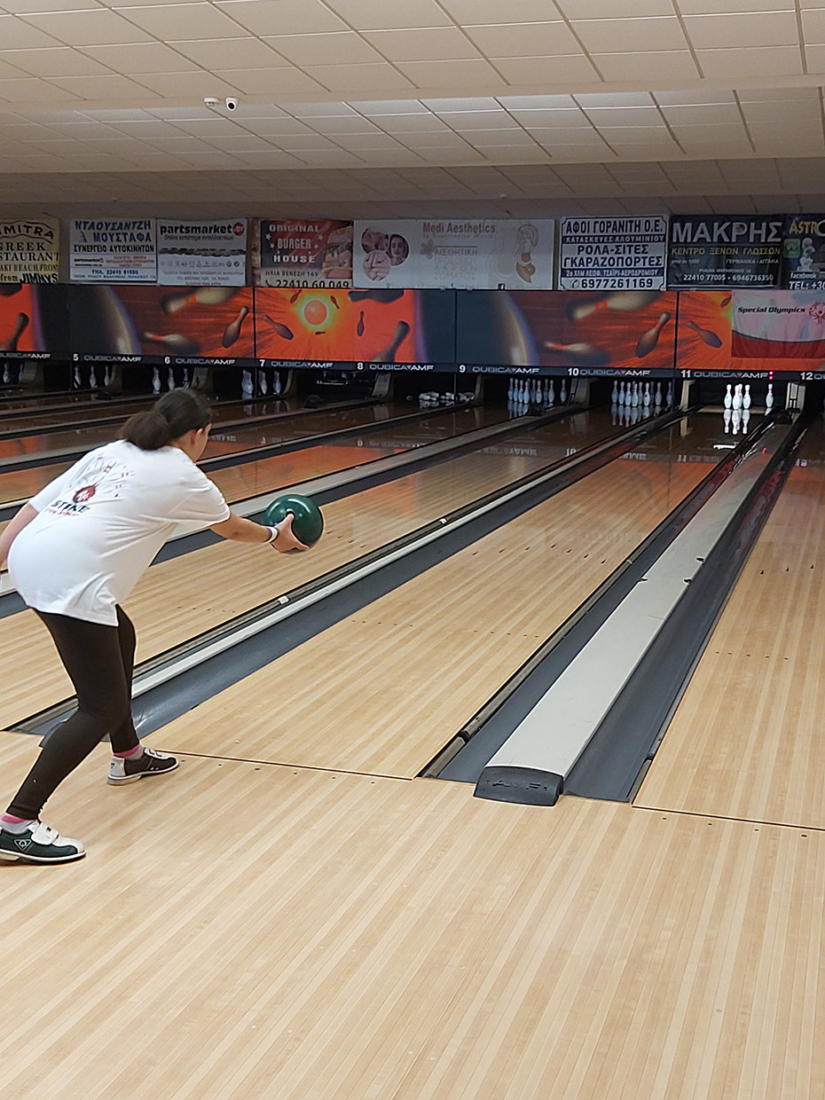 Φωτογραφία από μια νεαρή κοπέλα η οποία ετοιμάζεται να ρίξει μια βολή στον διάδρομο του bowling 