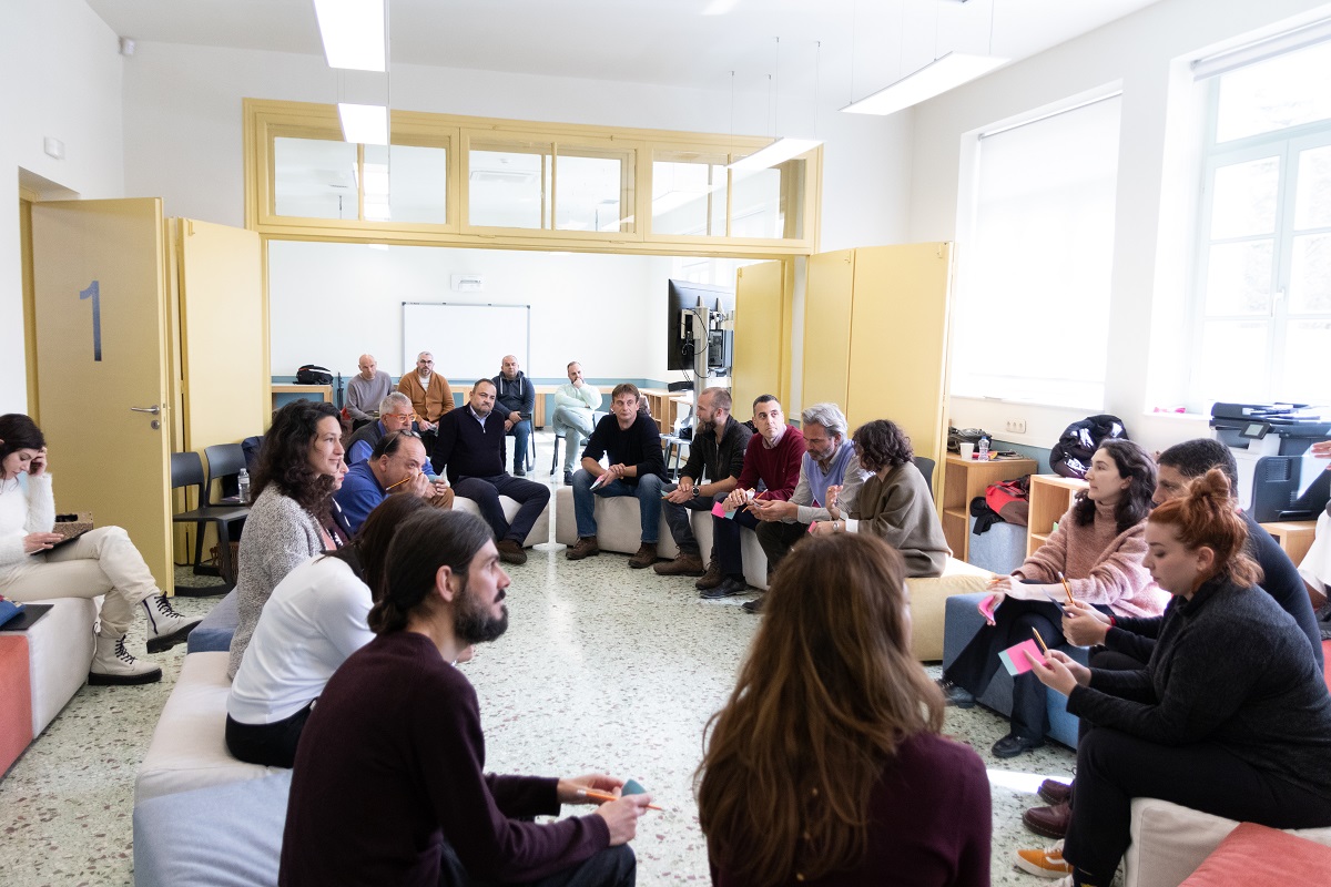 Πολλοί άνθρωποι κάθονται σε κύκλο και συζητούν.