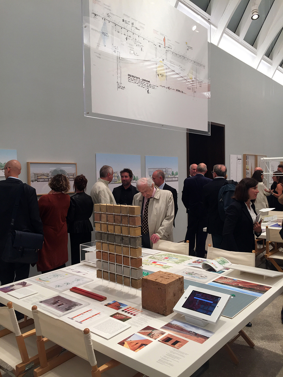 Κοντινή φωτογραφία από ένα τετράγωνο τραπέζι πάνω στο οποίο υπάρχουν περιγραφές και ένα μικρό τοιχάκι φτιαγμένο από πολλά μικρά τερτάγωνα τουβλάκιαδιαφορετικών υλικών και χρωμάτων 