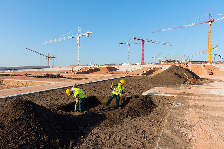 Δύο εργάτες που φοράν ετο ίδιο γιλέκο εργασίας και το ίδιο κράνος, σκάβουν ένα μεγάλο παρτέρι