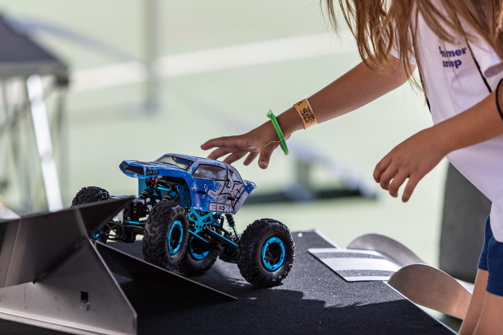 Ένα νεαρό κορίτσι παίζει με ένα μικρό off-road αυτοκίνητο 