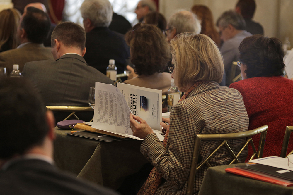 Μια γυναίκα που είναι μέρος του κοινού του συνεδρίου κοιτάζει το φυλλάδιο που είχε τοποθετηθεί στο τραπέζι