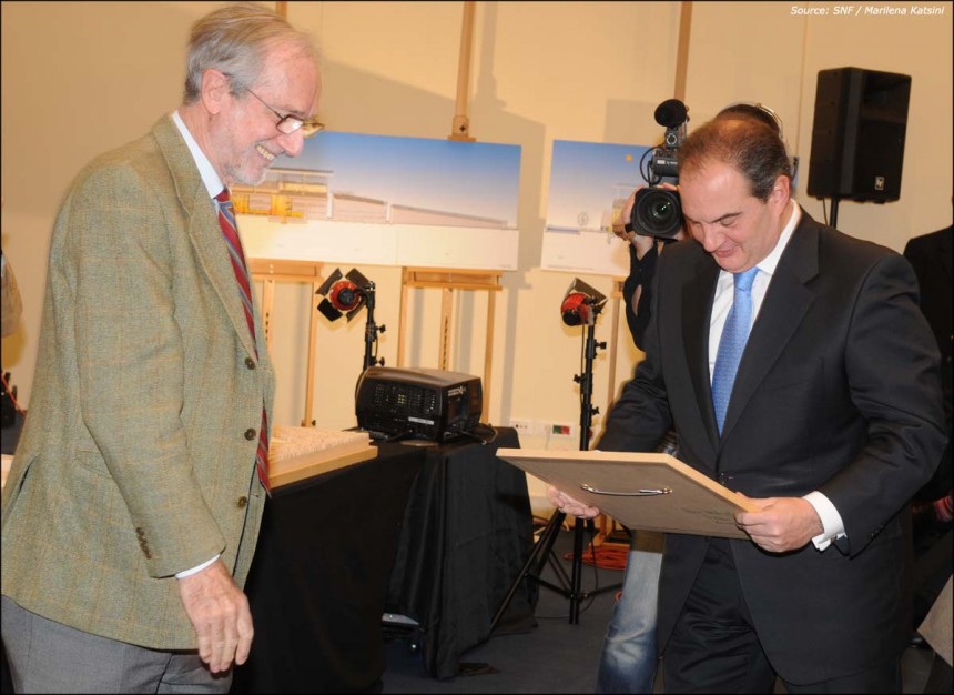 Ένας άντρας κρατάει ένα κάδρο στα χέρια του και το κοιτάει και ο άντρας που βρίσκεται δίπλα του τον κοιτά