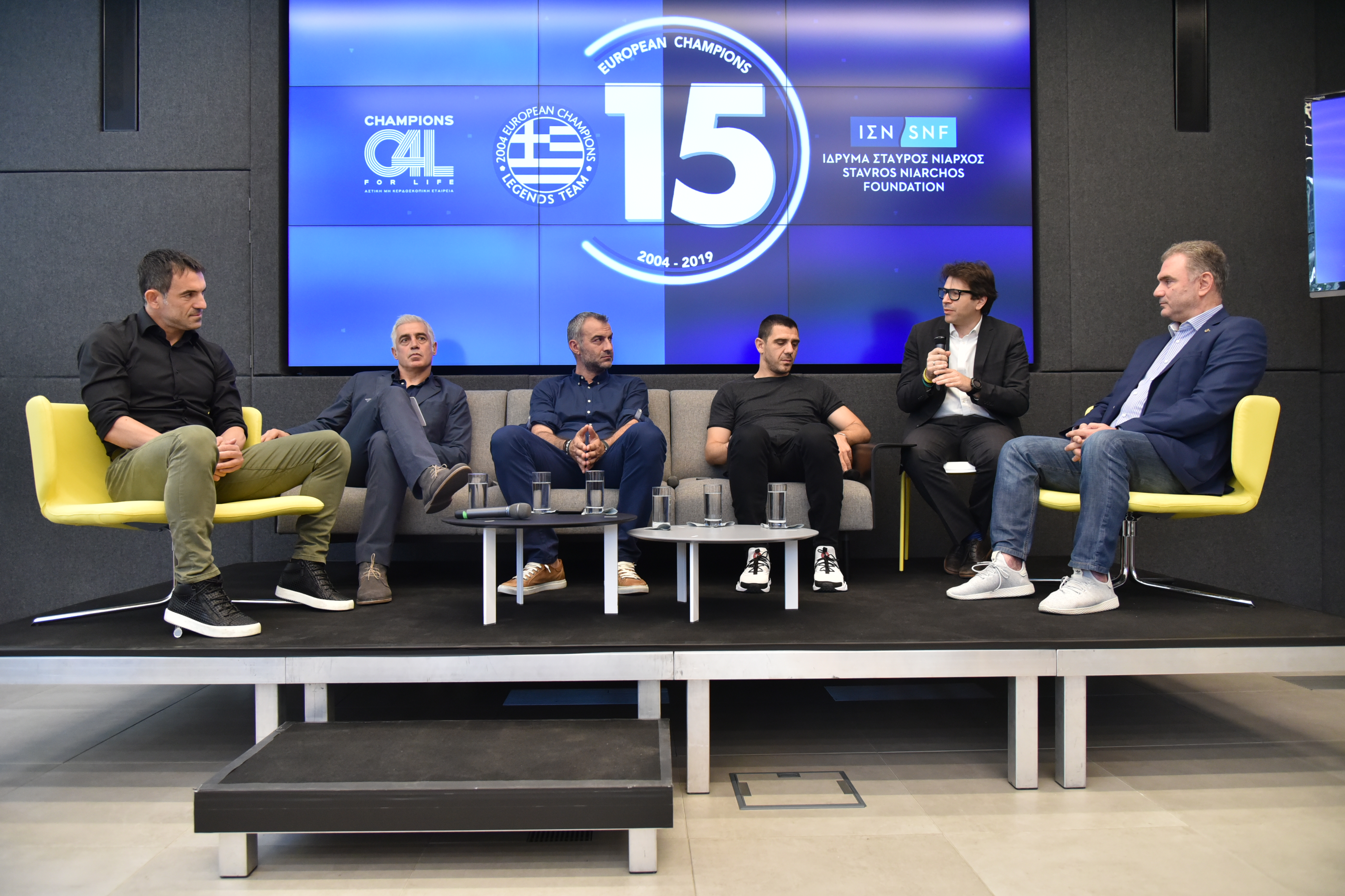 Έξι άντρες κάθονται και συζητούν μεταξύ τους σε ένα panel 