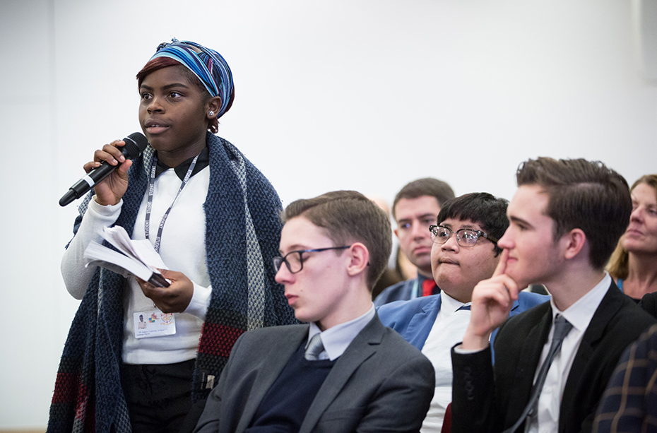 Μια νεαρή γυναίκα στο κοινό σηκώνεται για να κάνει μια ερώτηση 