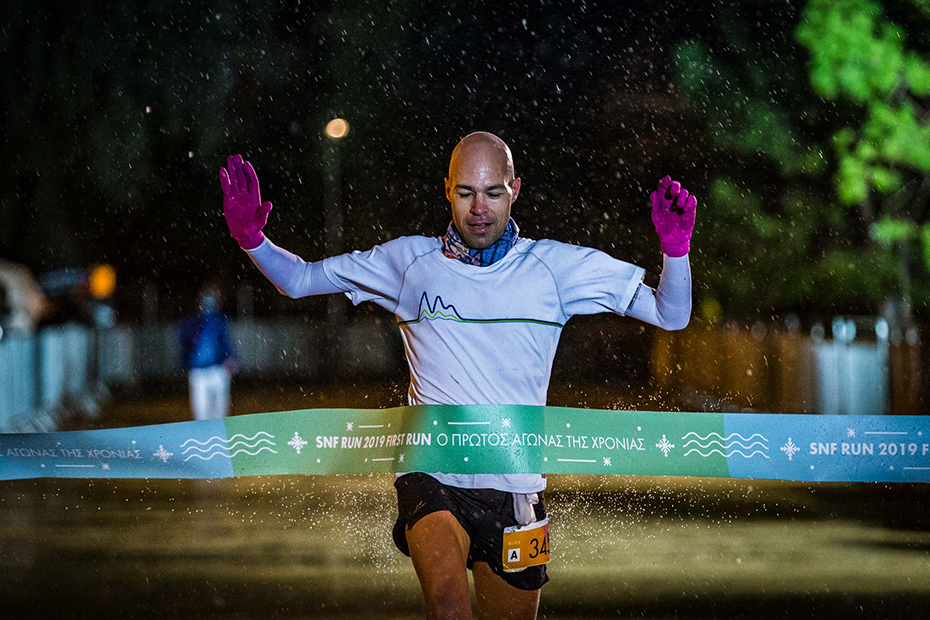 Ένας άνδρας τρέχει πάνω στην κορδέλα του αγώνα δρόμου Stavros Niarchos Foundation RUN 