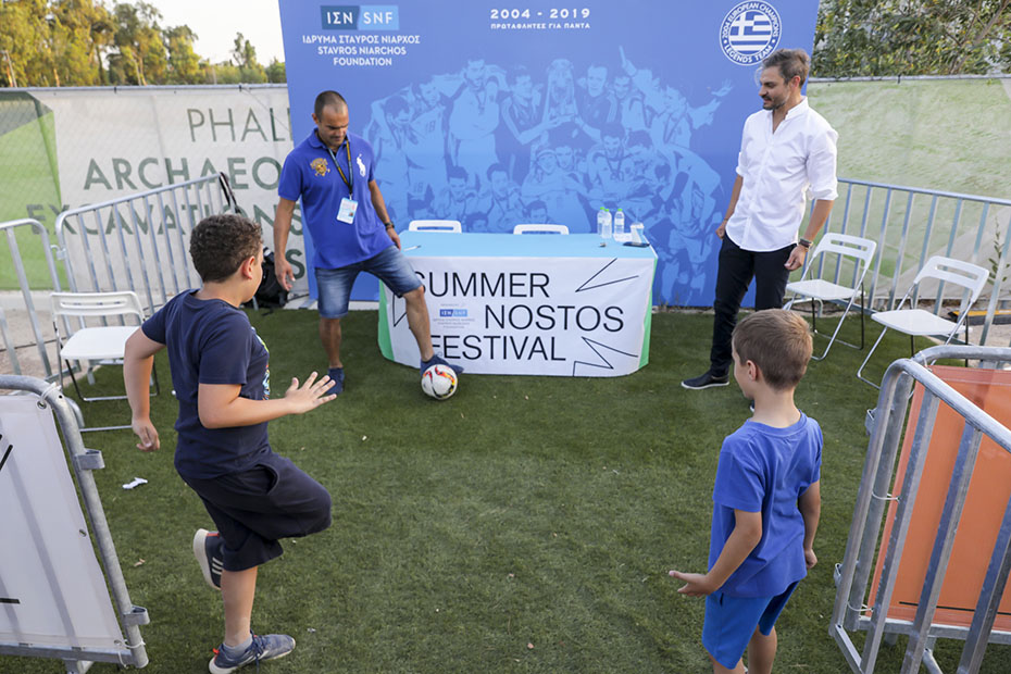 Δύο άντρες και δύο μικρά αγοράκια παίζουν ποδόσφαιρο στον χώρο του NOSTOS SUMMER FESTIVAL STAVROS NIARCHOS FOUNDATION