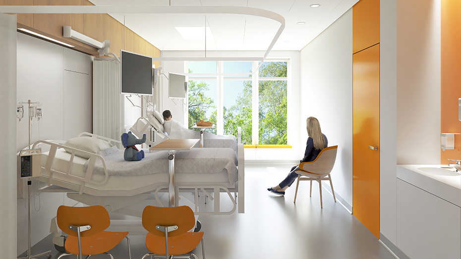 Φωτογραφία από το εσωτερικό ενός νοσοκομειακού δωματίου στο οποίο υπάρχουν δύο κρεβάτια και μία καρέκλα. Στο ένα κρεβάτι υπάρχει ένα λούτρινο ελεφαντάκι, στο άλλο κρεβάτι κάθεται ένας άντρας ασθενής και στην καρέκλα κάθεται μια γυναίκα η οποία κοιτάει προς το παράθυρο 