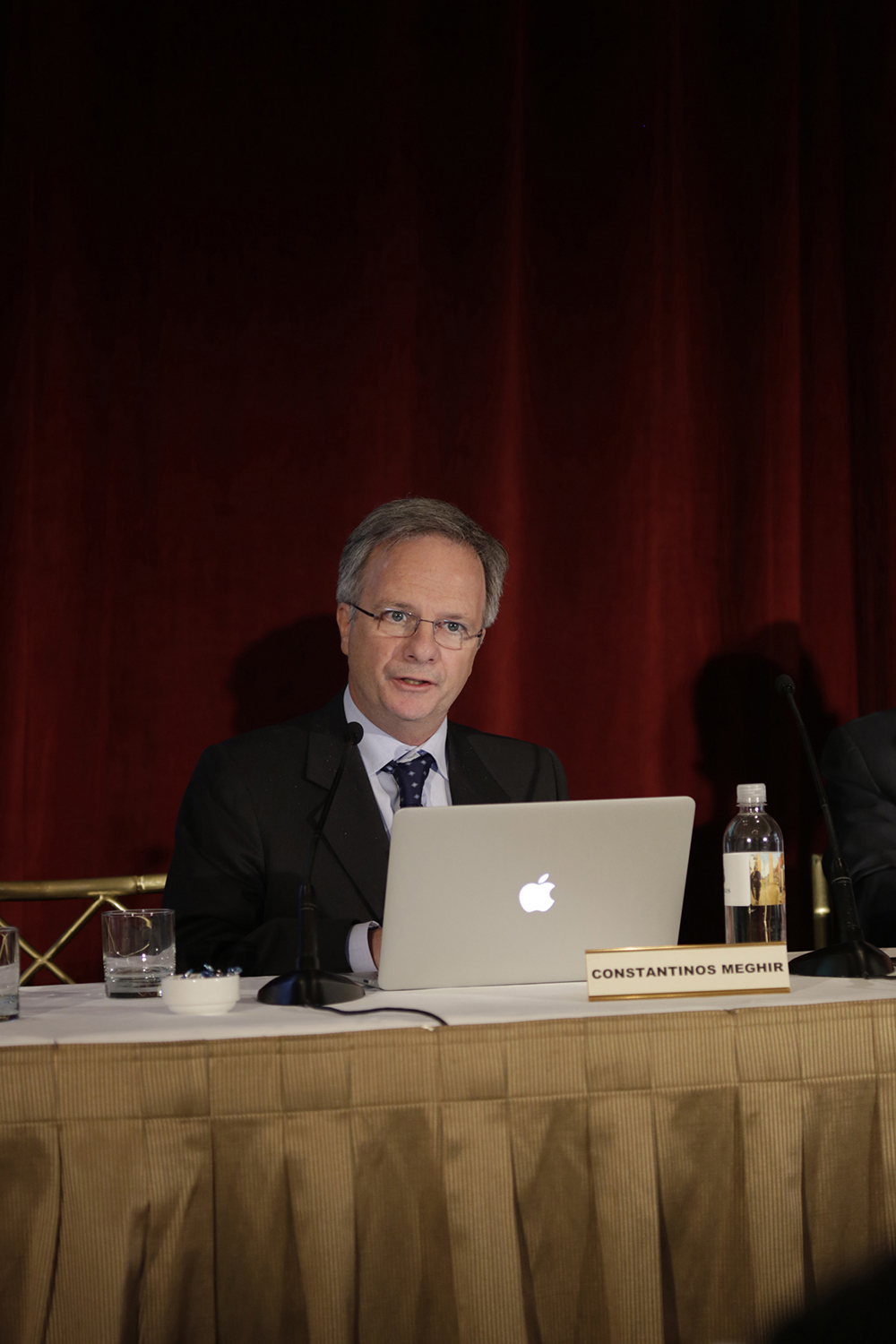 Ένας άνδρας που συμμετέχει στο συνέδριο κάθεται σε ένα τραπέζι με τον φορητό του υπολογιστή ανοιχτό