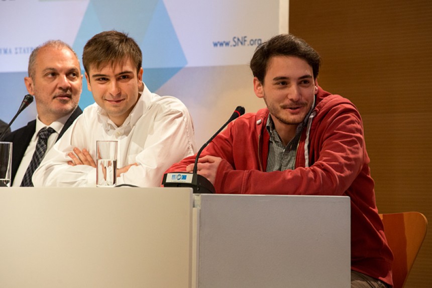 Δύο νέοι άνδρες κάθονται στο τραπέζι συνεδριάσεων στη σκηνή του Κέντρου Πολιτισμού Ίδρυμα Σταύρος Νιάρχος