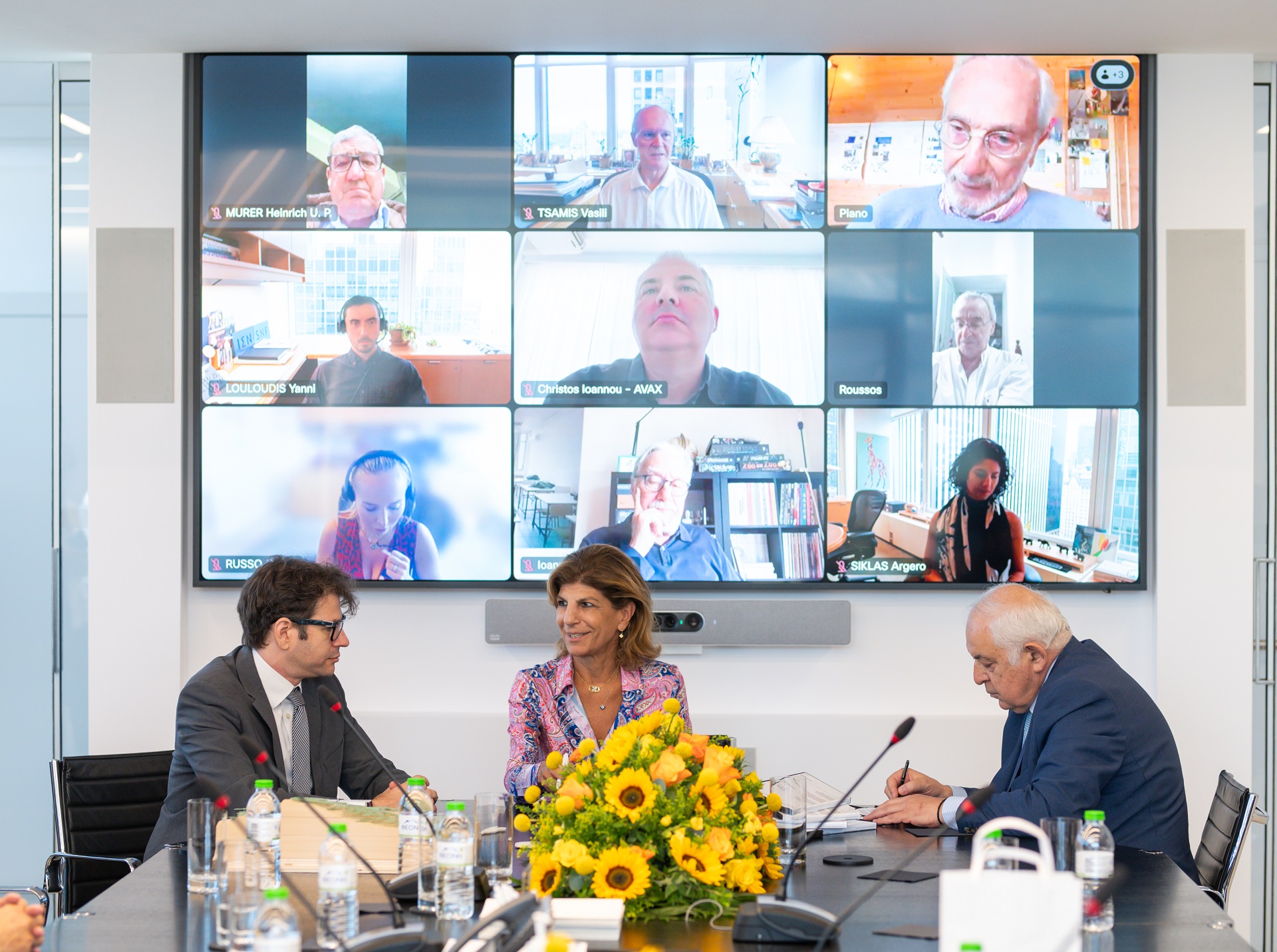 Δύο άντρες και μια γυναίκα μπροστά από ζωντανή σύνδεση με άλλα μέλη του Ιδρύματος Σταύρος Νιάρχος, υπογράφουν για την κατασκευή των τριών νέων νοσκομείων Ίδρυμα Σταύρος Νιάρχος 