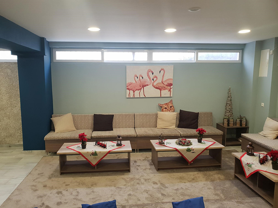 Φωτογραφία του εσωτερικού της Νέας Αίθουσας, η οποία διαθέτει έναν μακρύ καναπέ και τραπεζάκια