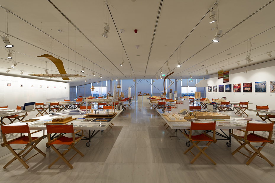 Μακρινή φωτογραφία που δείχνει έναν εσωτερικό χώρο στον οποίο υπάρχουν κάποια τετυράγωνα τραπέζια πάνω στα οποία υπάρχουν εικόνες και υπομνήματα