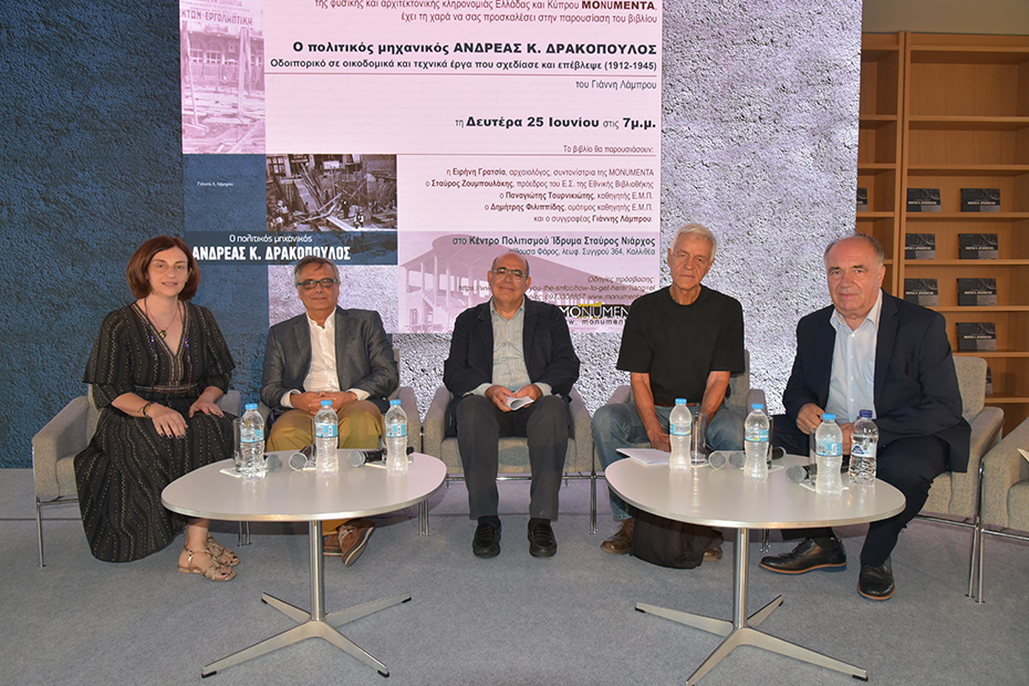 Τέσσερις άντρες και μια γυναίκα κάθονται σε καρέκλες πάνω στη σκηνή με τη μορφή ενός πάνελ και χαμογελούν για μια αναμνηστική φωτογραφία 