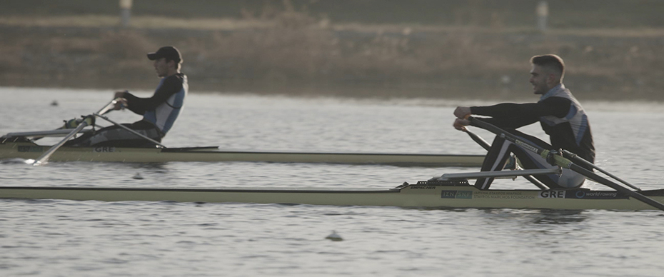Δυο νεαροί άντρες αθλητές κωπηλασίας, κάθονται στα κανό τους και κάνουν κουπί σε μια λίμνη  