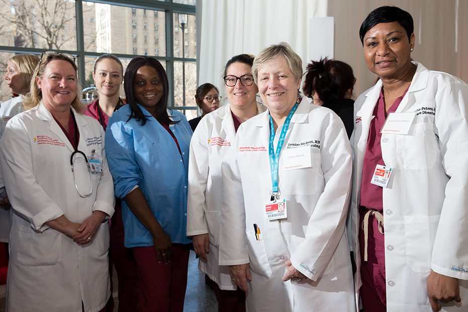 Μια ομάδα γιατρών από το νοσοκομείο New York-Presbyterian χαμογελούν και βγάζουν μια φωτογραφία μαζί