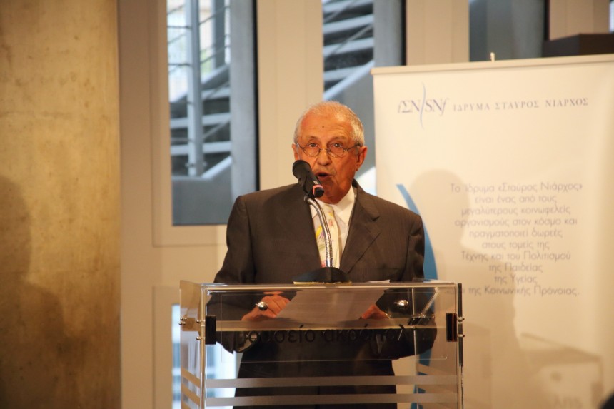 Ένας άντρας μιλάει στο βήμα και πίσω του υπάρχει ένα banner που έχει το λογότυπο του Ιδρύματος Σταύρος Νιάρχος