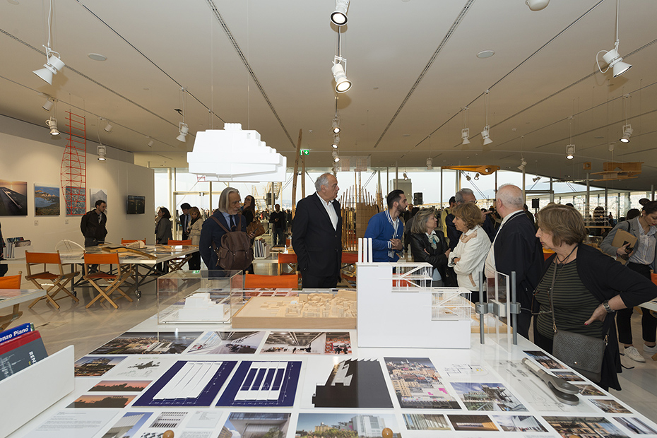 Φωτογραφία που δείχνει κόσμο να κοιτάει ένα τραπέζι γεμάτο σχέδια, υπομνήματα και μακέτες κτηρίων 