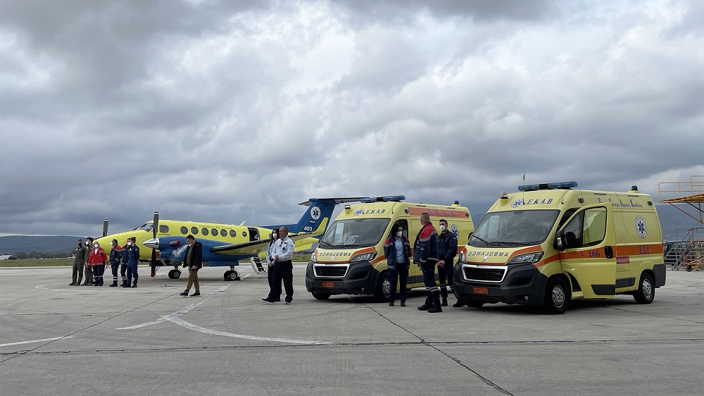 Φωτογραφία με μέλη του ΕΚΑΒ να στέκονται δίπλα από δύο ασθενοφόρα και ένα αεροπλάνο του ΕΚΑΒ