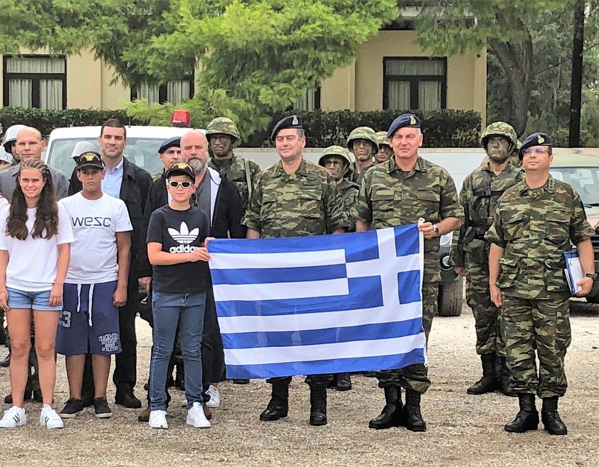 Μέλη του Σταύρου Νιάρχου στέκονται μαζί με μέλη της Ελληνικής Στρατιωτικής Ακαδημίας που κρατούν μια ελληνική σημαία