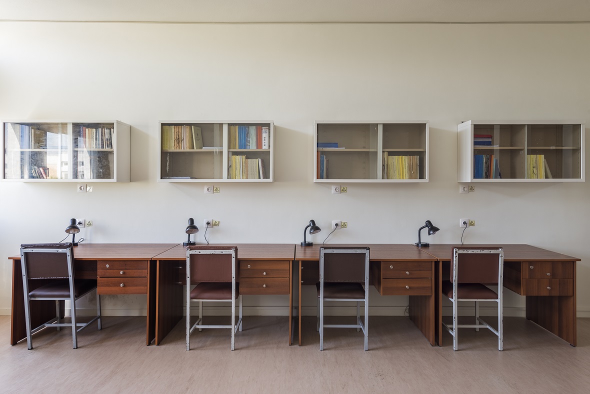 Τέσσερα γραφεία με φωτιστικά, καρέκλες και βιβλιοθήκες.