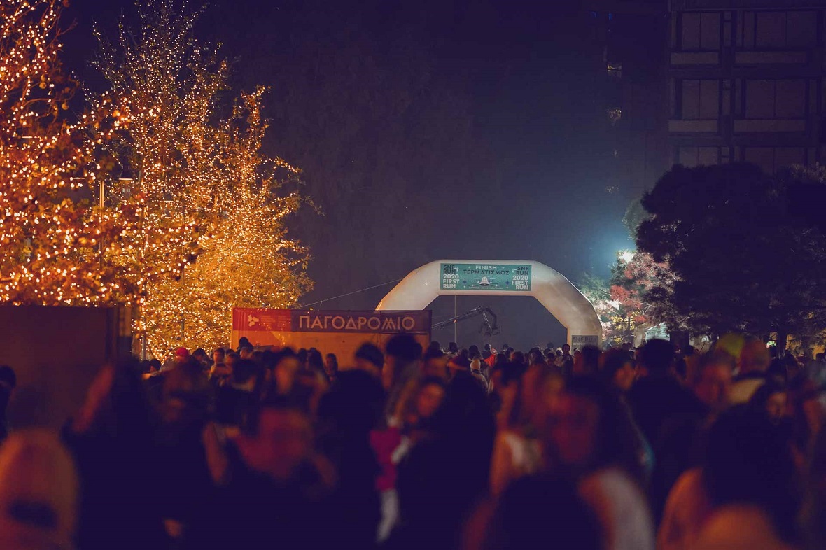 Πλήθος ανθρώπων σε εξωτερικό χώρο στον οποίο υπάρχει η γραμή τερματισμού ενός αγώνα δρόμου και ένα παγοδρόμιο