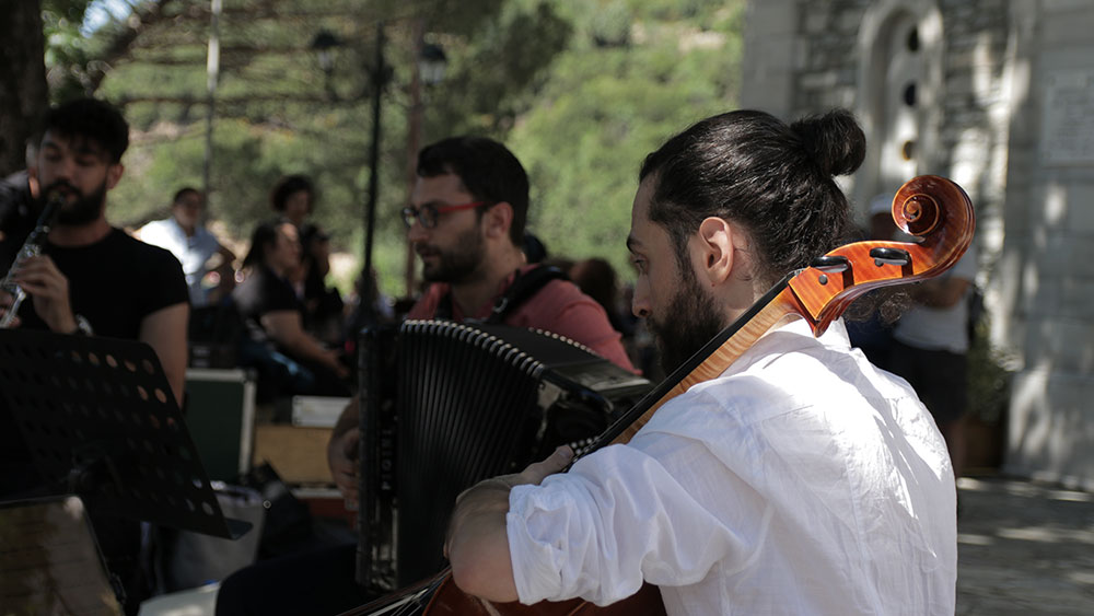Τρεις άντρες κάθονται μαζί και παίζουν μουσικά όργανα 