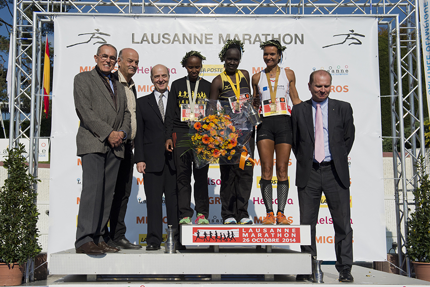 Οι νικητές του μαραθωνίου Lasaunne χαμογελούν για μια φωτογραφία κρατώντας λουλούδια και τα βραβεία τους