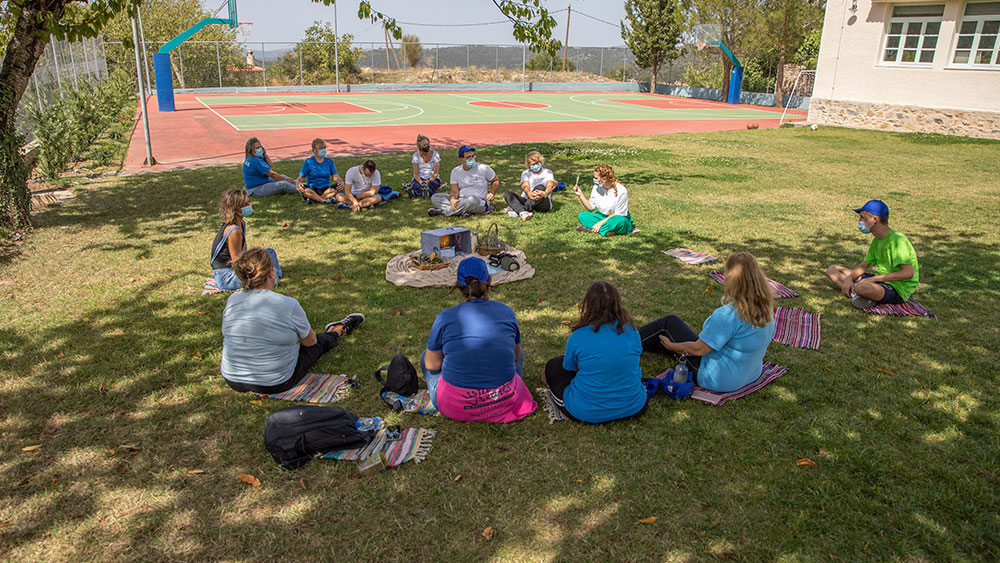 Οι αθλητές των Special Olympics Hellas και οι γονείς τους κάθονται στο γρασίδι σε κύκλο