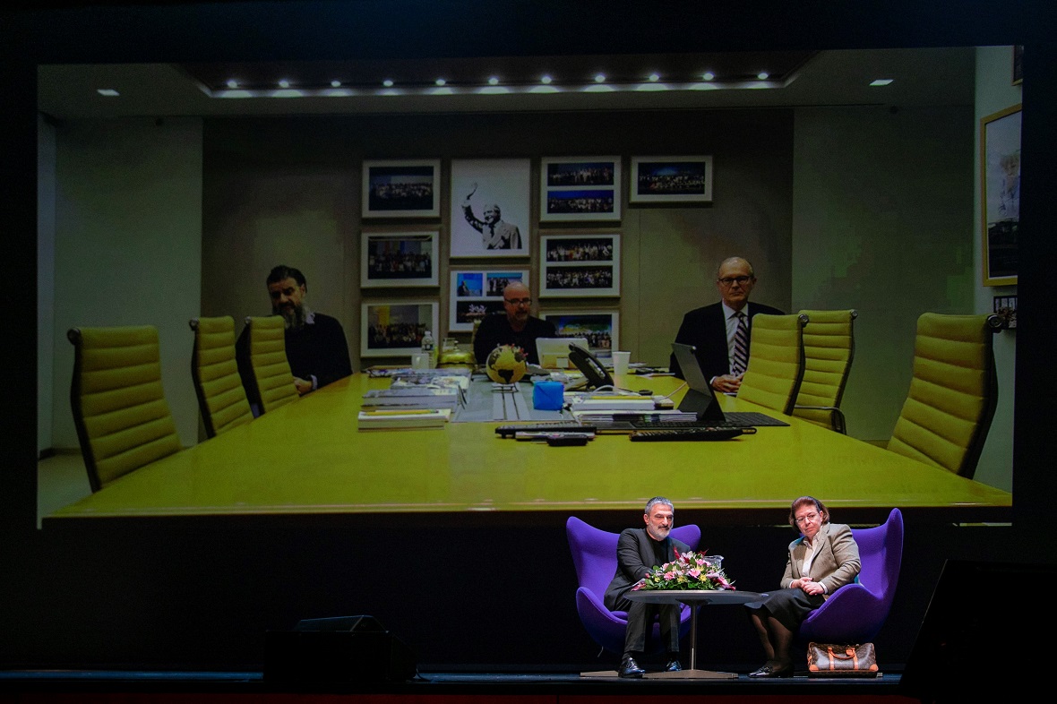 Βιντεοκλήση ζωντανής σύνδεσης με τον Ανδρέα Δρακόπουλο, πρόεδρο του Ιδρύματος Σταύρος Νιάρχος, και δύο άλλους άνδρες στη σκηνή της Εθνικής Λυρικής Σκηνής, όπου μια γυναίκα και ένας άντρας είναι καθισμένοι